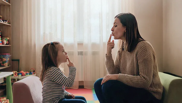 A speech therapy session between a specialist and a young girl