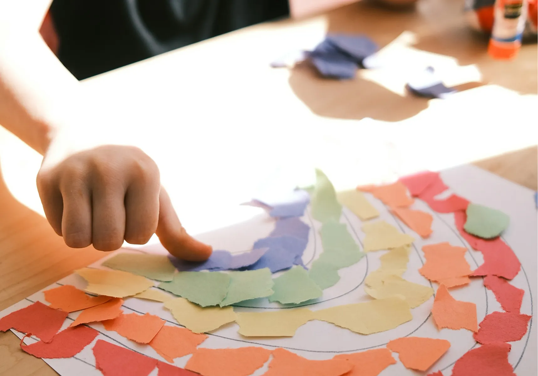 A child making a rainbow paper collage